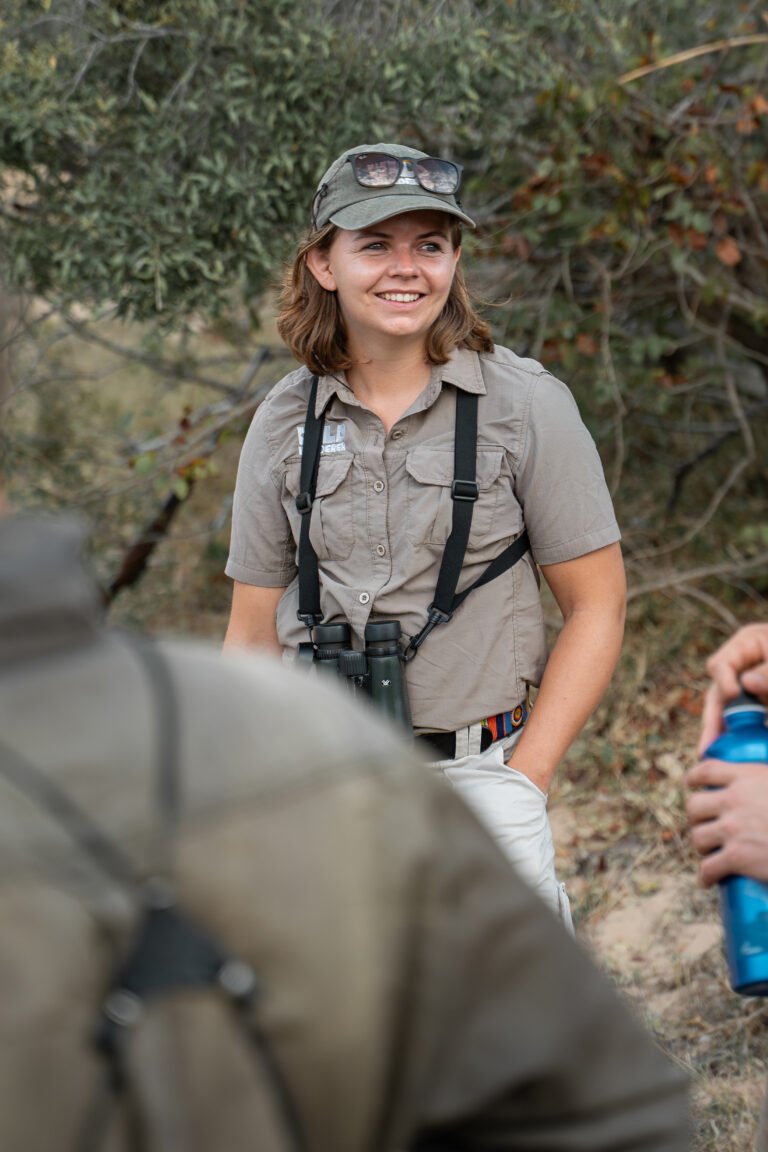 Daphne in gesprek met een deelnemer tijdens de Primitive Trail wandelsafari in Greater Kruger, met de Afrikaanse natuur op de achtergrond.